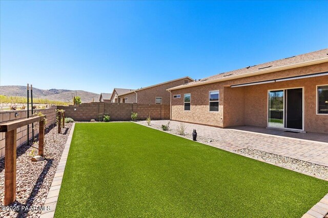 view of yard featuring a patio, a fenced backyard, and a mountain view
