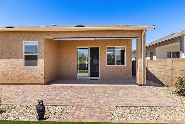back of house featuring stucco siding, fence, and a patio