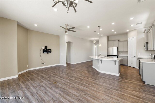 kitchen with gray cabinets, arched walkways, freestanding refrigerator, open floor plan, and ceiling fan