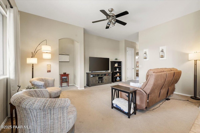 living room with baseboards, arched walkways, ceiling fan, and carpet floors