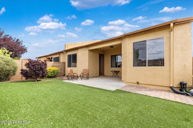 back of house with a yard, a patio area, stucco siding, and fence
