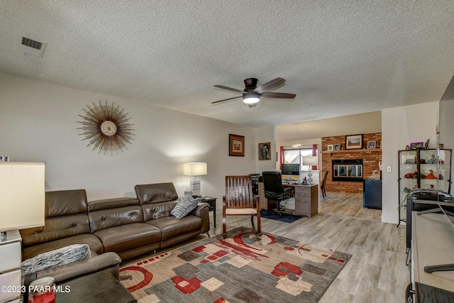 3096 Montana Dr, Prescott, AZ 86301 - living room featuring visible vents, a brick fireplace, ceiling fan, light wood-type flooring, and a textured ceiling