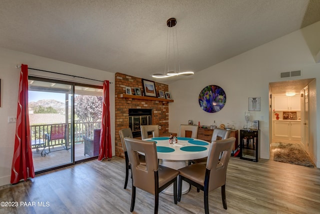 3096 Montana Dr, Prescott, AZ 86301 - dining area with light wood-style floors, a brick fireplace, visible vents, and vaulted ceiling