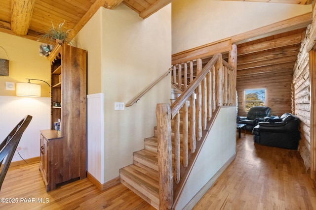 staircase with hardwood / wood-style flooring, wooden ceiling, vaulted ceiling with beams, and log walls