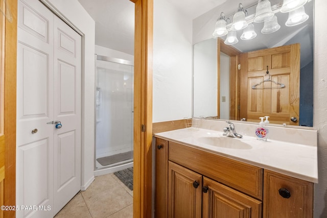 bathroom featuring tile patterned flooring, vanity, and a shower with door