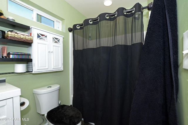 bathroom featuring toilet, walk in shower, and vanity