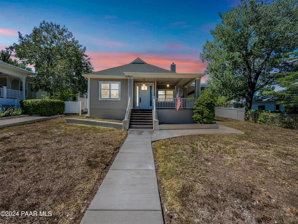 view of front of property with covered porch and a yard