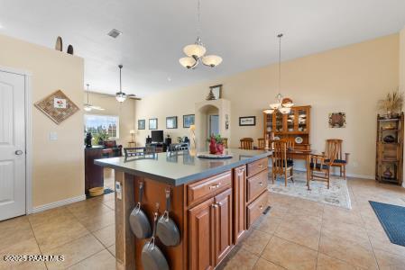 kitchen featuring pendant lighting, ceiling fan with notable chandelier, light tile patterned flooring, and a kitchen island