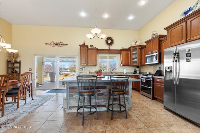 kitchen with decorative light fixtures, a kitchen breakfast bar, a kitchen island, stainless steel appliances, and a high ceiling