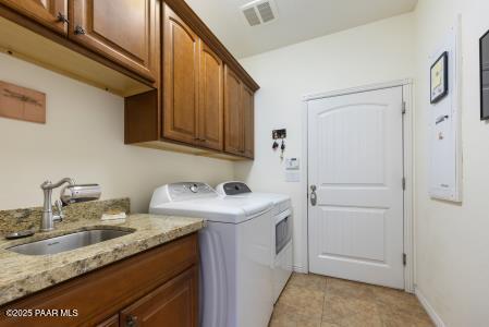 laundry room featuring sink, light tile patterned floors, washing machine and dryer, and cabinets