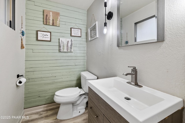 707 Apache Dr, Dewey-Humboldt, AZ 86327 - half bathroom with wooden walls, wood finished floors, toilet, vanity, and a textured wall