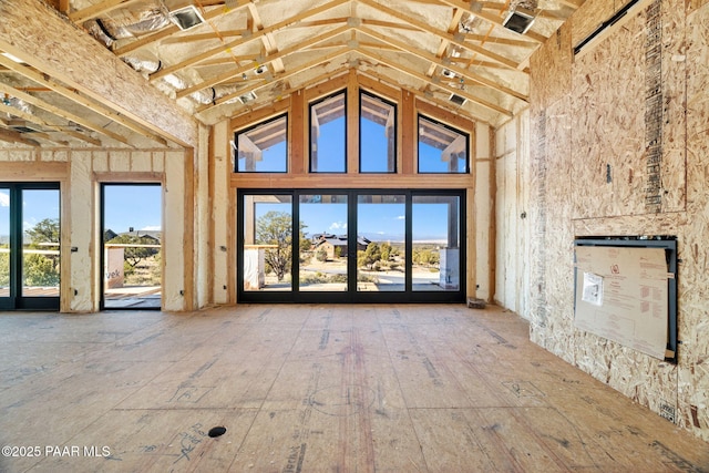 unfurnished living room featuring plenty of natural light and high vaulted ceiling