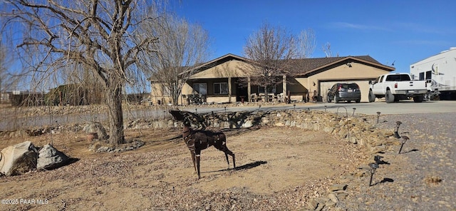 ranch-style home with driveway, a garage, and stucco siding