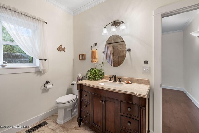 bathroom featuring toilet, vanity, baseboards, visible vents, and crown molding