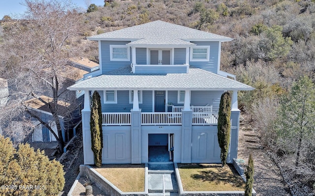 coastal home with roof with shingles and a balcony