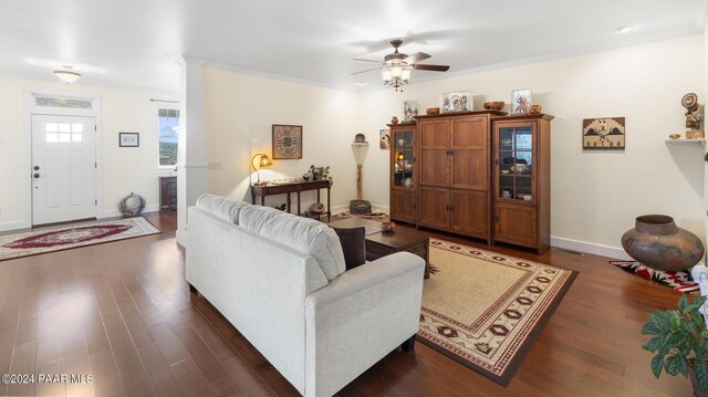 living area with baseboards, dark wood-style flooring, a ceiling fan, and crown molding