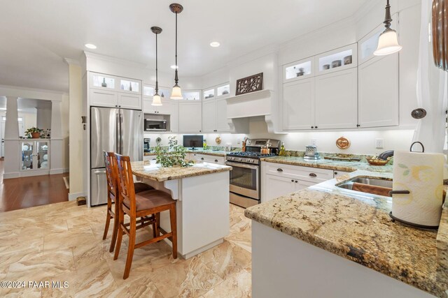 kitchen featuring stainless steel appliances, glass insert cabinets, white cabinetry, and pendant lighting