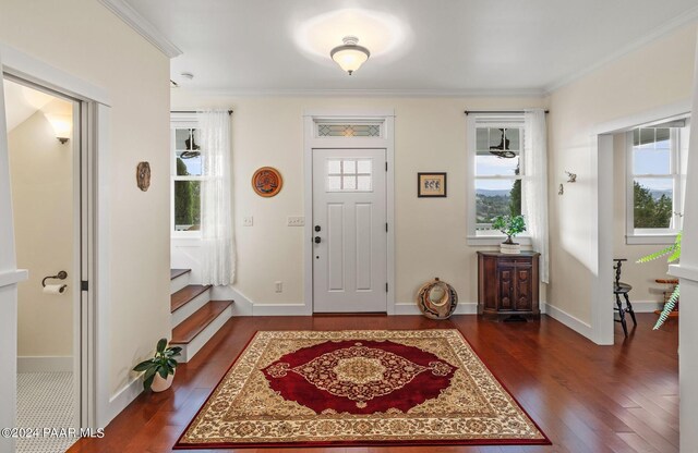 entryway with ornamental molding, dark wood-type flooring, baseboards, and stairs