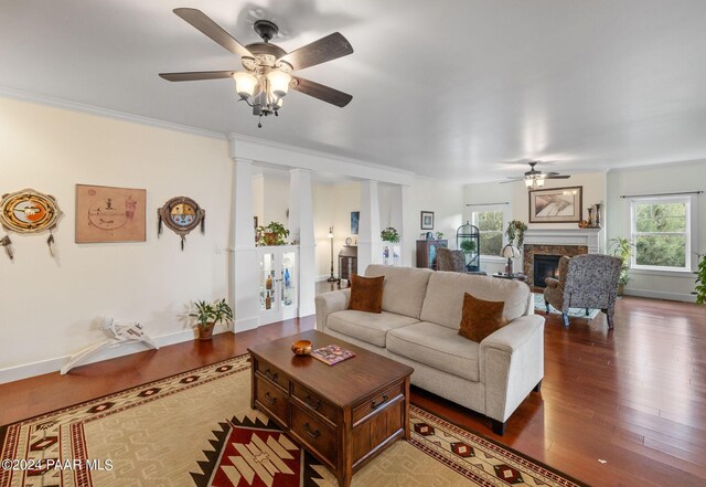 living area with a fireplace, plenty of natural light, wood finished floors, and crown molding