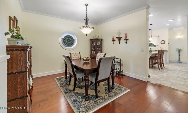 dining room with dark wood-style flooring, crown molding, and baseboards