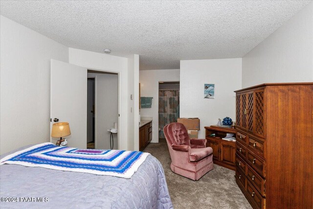 bedroom with carpet flooring, a textured ceiling, and ensuite bath