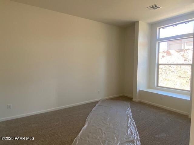 spare room with dark carpet