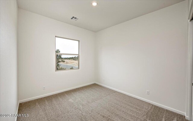 carpeted spare room featuring baseboards, visible vents, and recessed lighting