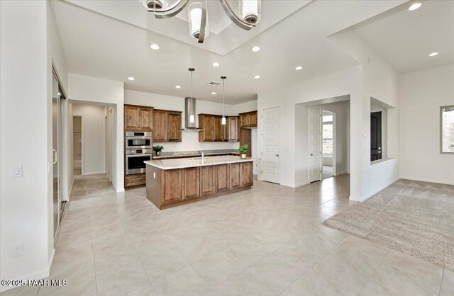 kitchen featuring wall chimney range hood, recessed lighting, light countertops, open floor plan, and stainless steel double oven