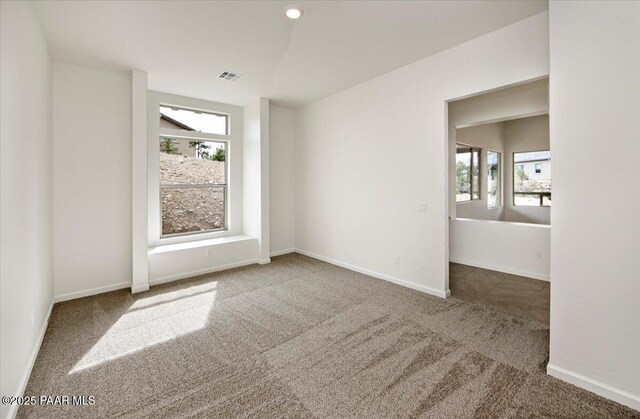 spare room featuring visible vents, a wealth of natural light, carpet flooring, and baseboards