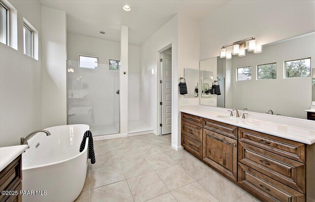 bathroom with a freestanding tub, vanity, a tile shower, and tile patterned flooring