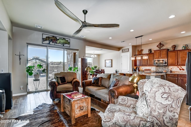 living room featuring wood-type flooring and ceiling fan with notable chandelier