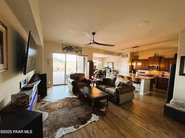 living room featuring ceiling fan with notable chandelier and dark hardwood / wood-style floors