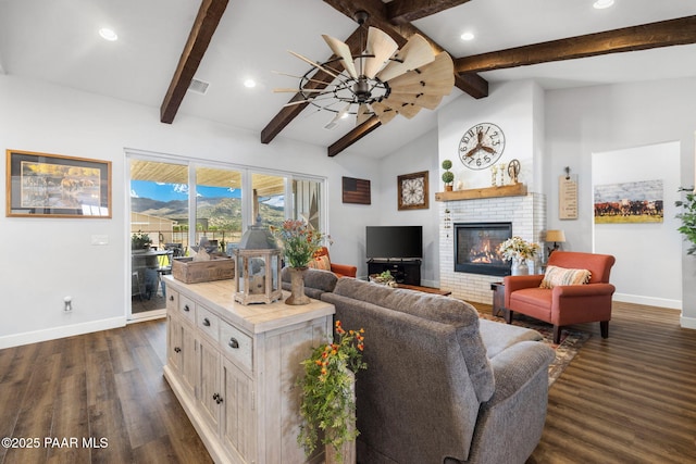 living room with ceiling fan, vaulted ceiling with beams, dark wood-type flooring, and a fireplace