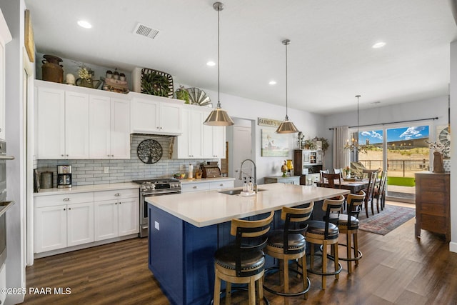 kitchen with decorative light fixtures, white cabinetry, and high end stove