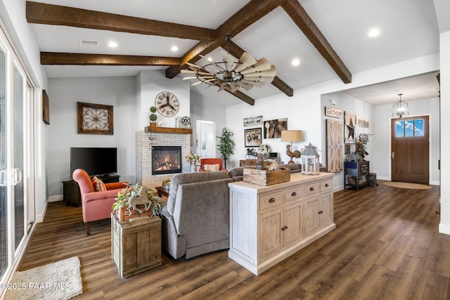 living room featuring ceiling fan with notable chandelier, dark hardwood / wood-style floors, vaulted ceiling with beams, and a brick fireplace