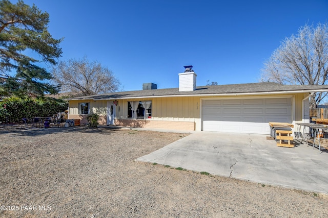 single story home with concrete driveway, brick siding, a chimney, and an attached garage