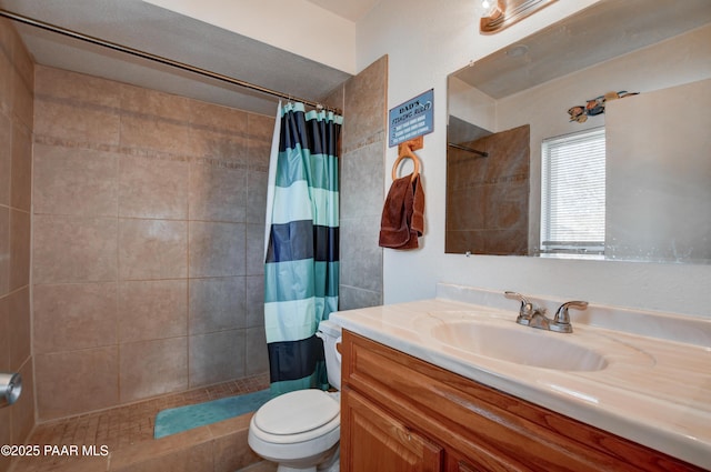 bathroom featuring toilet, tiled shower, and vanity