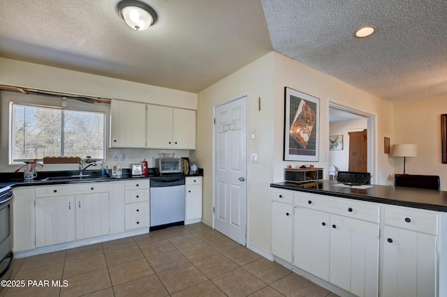 kitchen with light tile patterned flooring, a sink, white cabinetry, dishwasher, and dark countertops