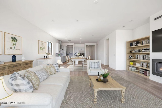 living area with a glass covered fireplace, light wood finished floors, and recessed lighting