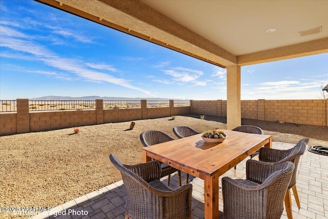 view of patio / terrace featuring a mountain view, outdoor dining area, a fenced backyard, and visible vents