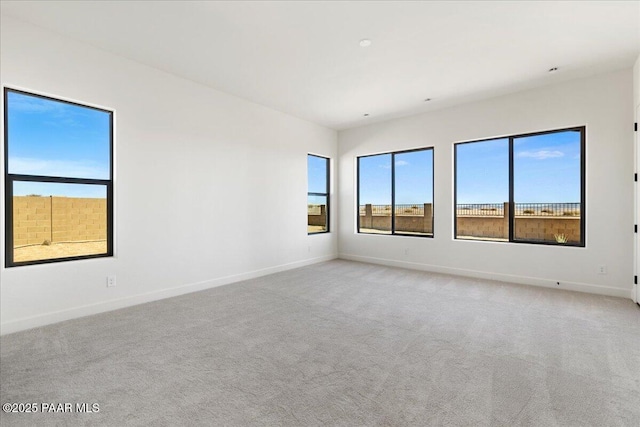 unfurnished room featuring light carpet and baseboards