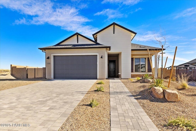 view of front of home with an attached garage, fence, and decorative driveway