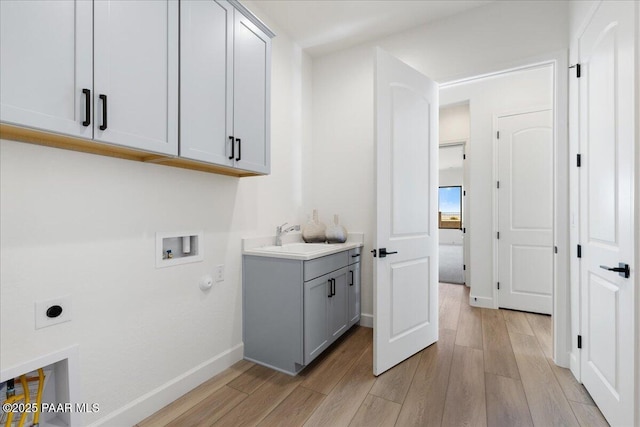 laundry area featuring cabinet space, electric dryer hookup, light wood-type flooring, washer hookup, and a sink