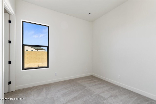 empty room featuring light carpet and baseboards