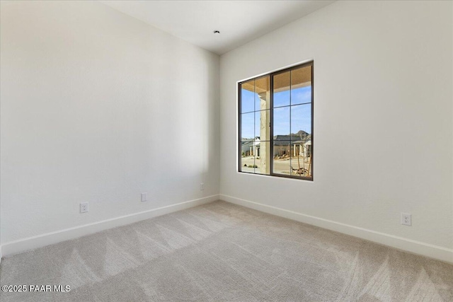 unfurnished room with light carpet and baseboards