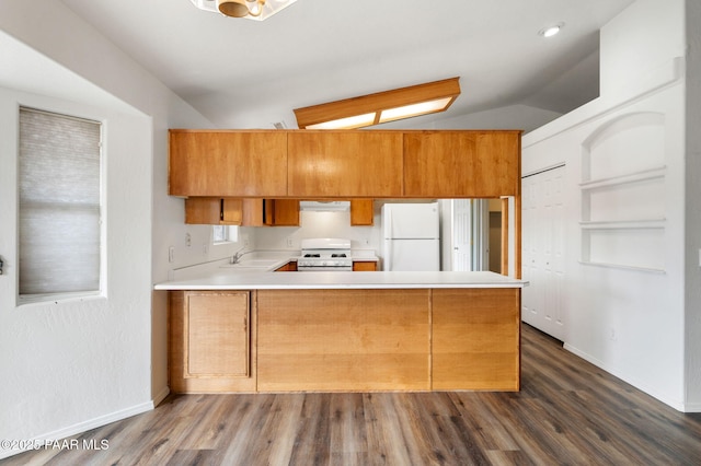 kitchen featuring light countertops, lofted ceiling, brown cabinets, a peninsula, and white appliances