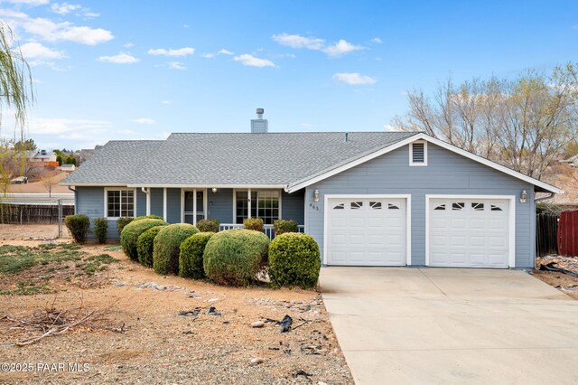 ranch-style house featuring a garage, concrete driveway, and fence