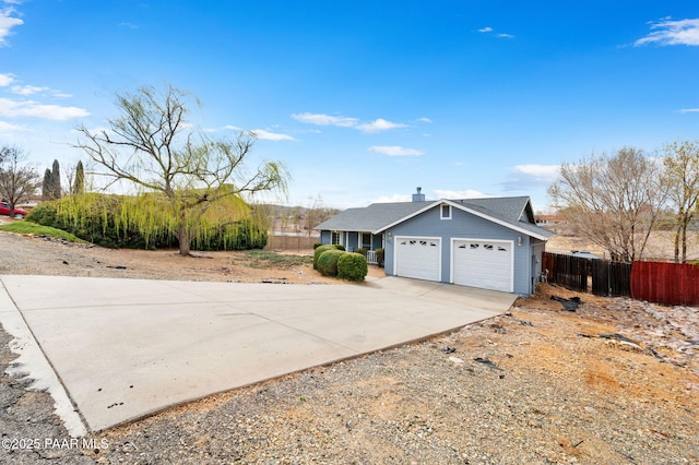 exterior space with driveway, a chimney, a garage, and fence