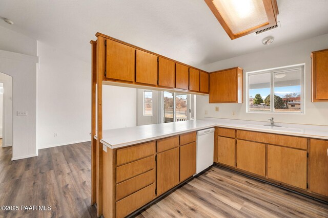 kitchen featuring visible vents, a sink, white appliances, arched walkways, and a peninsula