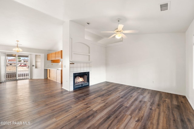 unfurnished living room with visible vents, dark wood finished floors, lofted ceiling, a fireplace, and ceiling fan